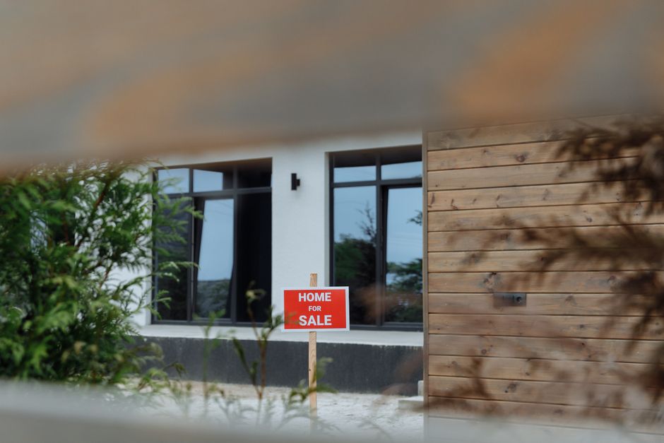 A real estate 'Sold' sign in the front yard of a beautiful, charming home on a sunny day, signifying a successful and positive property transaction.